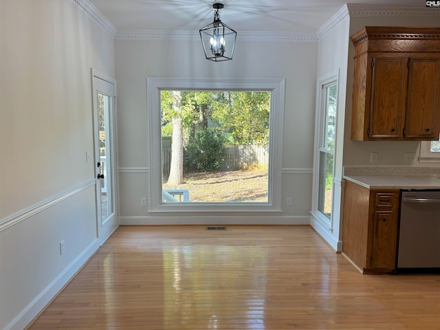 unfurnished dining area featuring light hardwood / wood-style floors, an inviting chandelier, and crown molding