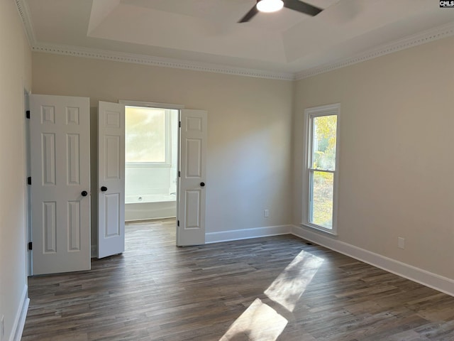 empty room with ornamental molding, a tray ceiling, ceiling fan, and dark wood-type flooring