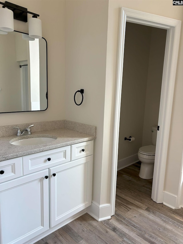 bathroom with hardwood / wood-style floors, vanity, and toilet