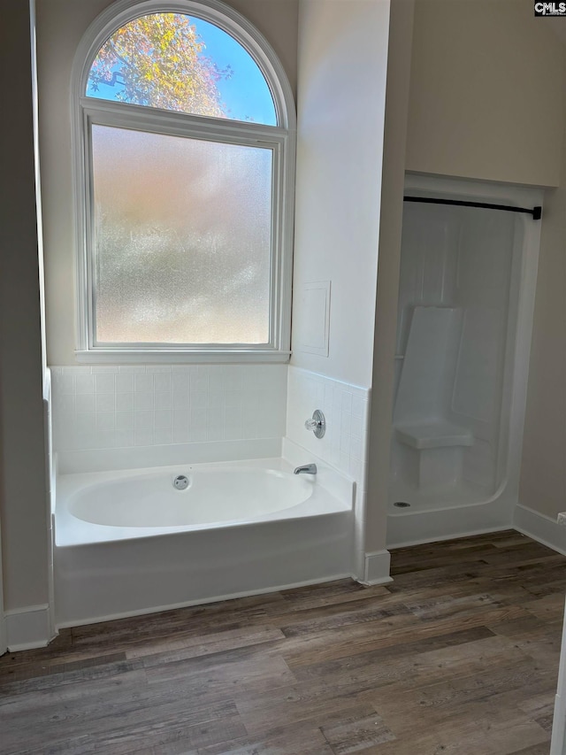 bathroom with wood-type flooring and a tub to relax in