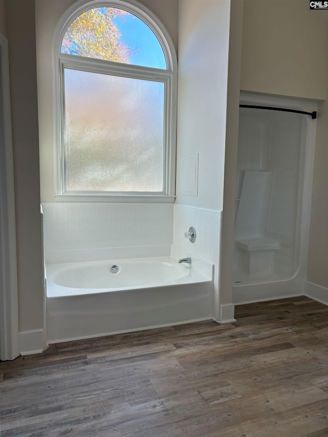 bathroom featuring a bath, hardwood / wood-style floors, and plenty of natural light