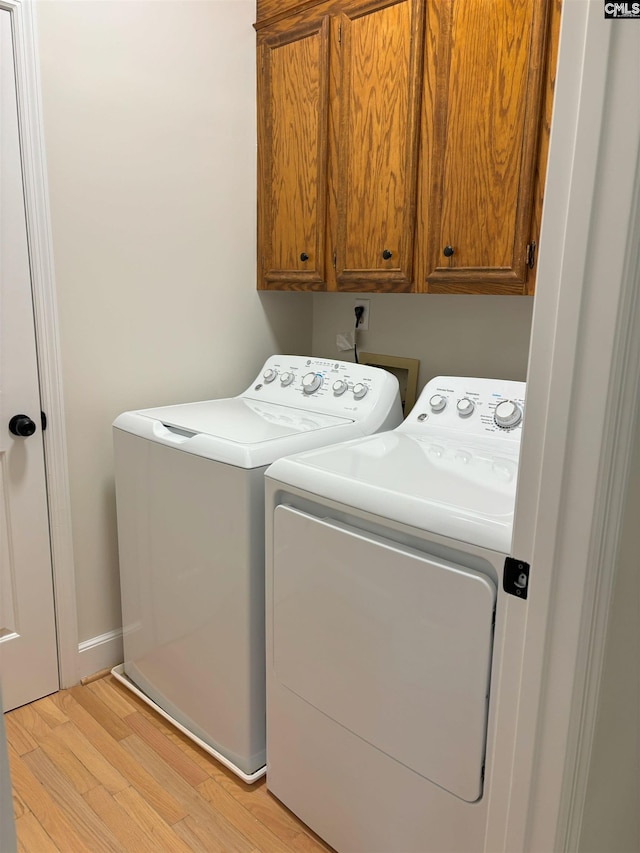 washroom featuring cabinets, light wood-type flooring, and separate washer and dryer