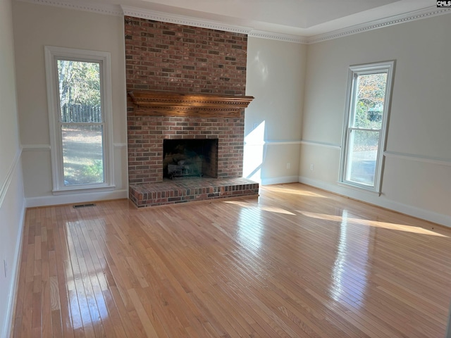 unfurnished living room with crown molding, a fireplace, and light wood-type flooring