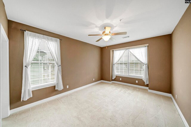 carpeted empty room with ceiling fan and plenty of natural light