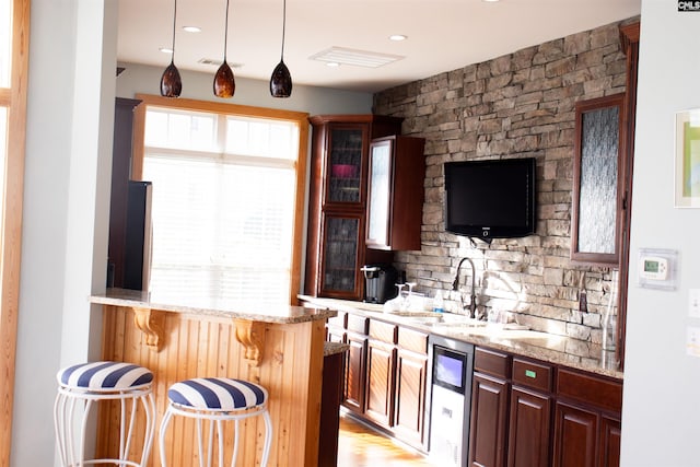 bar with light hardwood / wood-style floors, light stone counters, and a wealth of natural light