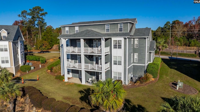 rear view of property featuring a lawn and a balcony