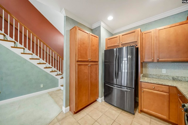 kitchen with light stone countertops, tasteful backsplash, stainless steel fridge, light tile patterned floors, and ornamental molding