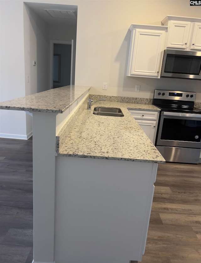 kitchen featuring kitchen peninsula, appliances with stainless steel finishes, dark hardwood / wood-style floors, and white cabinetry