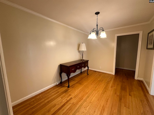 unfurnished room featuring light wood-type flooring, an inviting chandelier, and crown molding