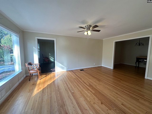 interior space with crown molding, ceiling fan with notable chandelier, and light wood-type flooring