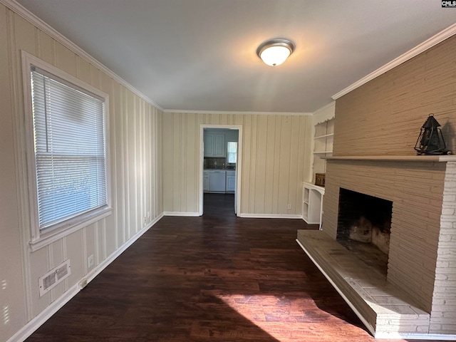 unfurnished living room with crown molding, dark hardwood / wood-style flooring, a fireplace, and built in shelves