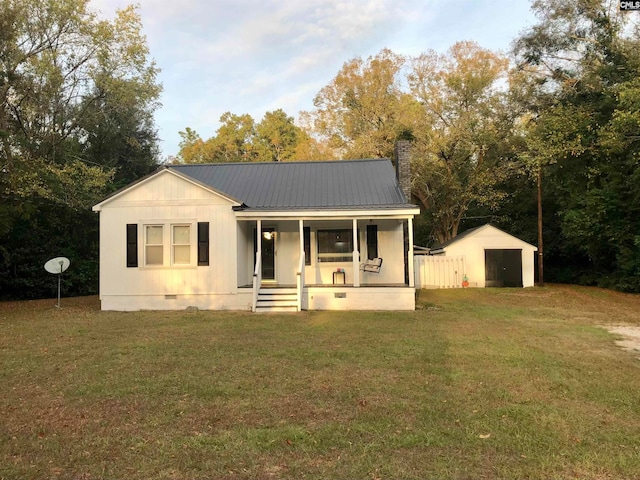 view of front of property featuring covered porch, a storage unit, and a front lawn