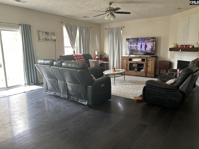 living room with ceiling fan, a textured ceiling, and hardwood / wood-style flooring