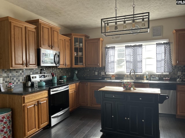 kitchen featuring sink, dark wood-type flooring, tasteful backsplash, a kitchen island, and appliances with stainless steel finishes