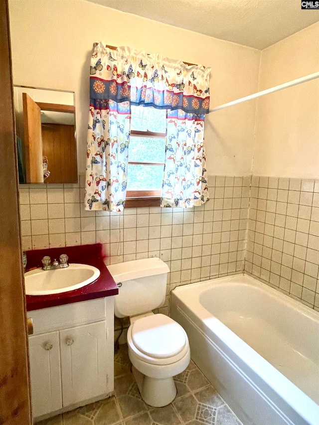 bathroom with vanity, tile patterned floors, a bathing tub, toilet, and tile walls