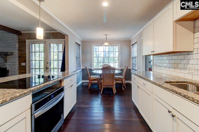 kitchen with dark wood-type flooring, black electric stovetop, oven, decorative light fixtures, and white cabinetry