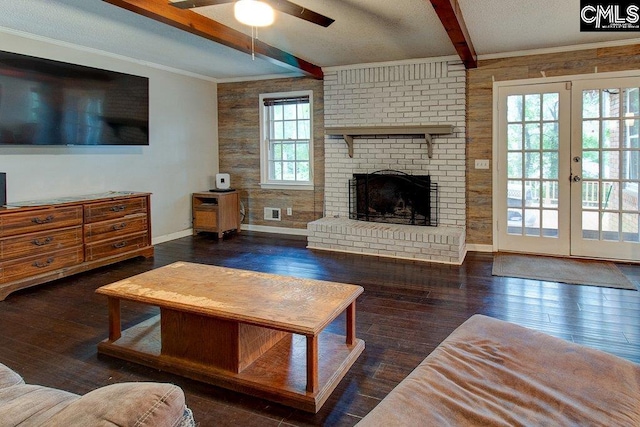 living room with french doors, a brick fireplace, ceiling fan, dark wood-type flooring, and beamed ceiling