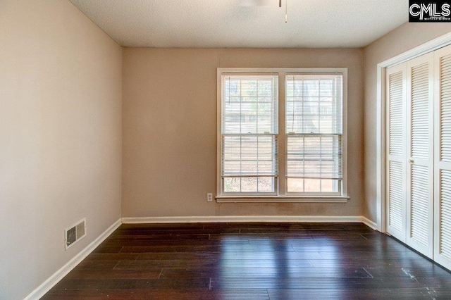 interior space featuring a textured ceiling, ceiling fan, and dark wood-type flooring