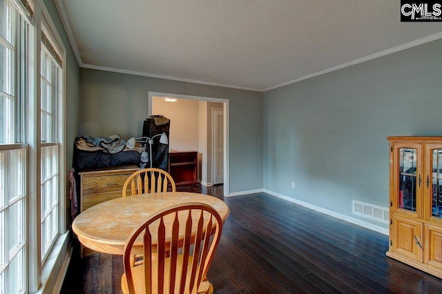 dining area with a textured ceiling, ornamental molding, and dark wood-type flooring