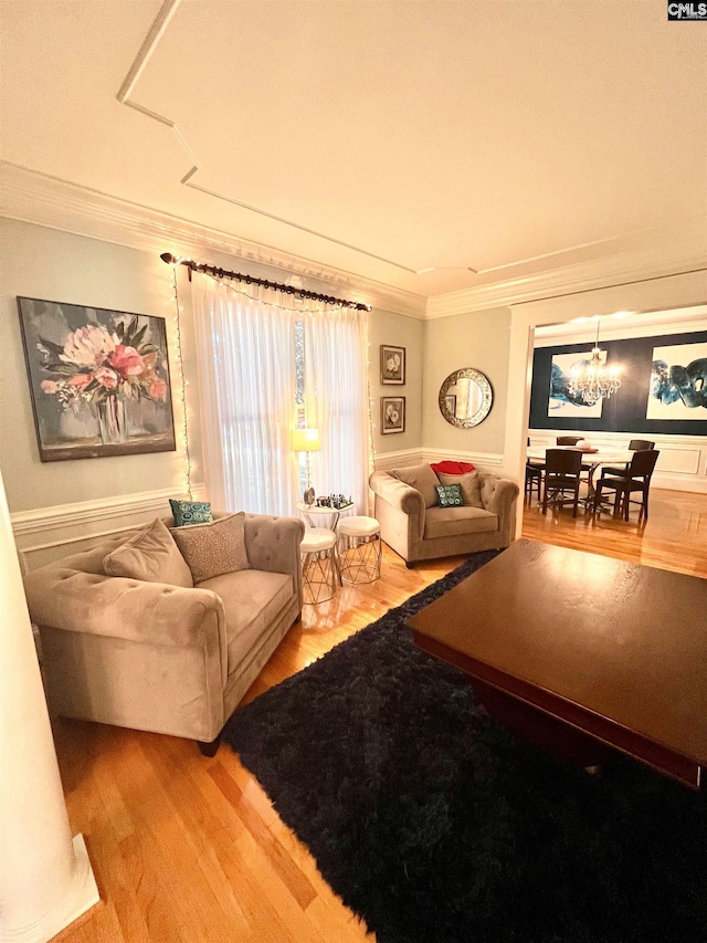 living room with wood-type flooring, crown molding, and a chandelier