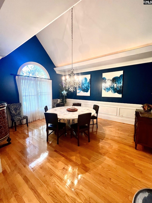 dining space with a chandelier, vaulted ceiling, and hardwood / wood-style flooring