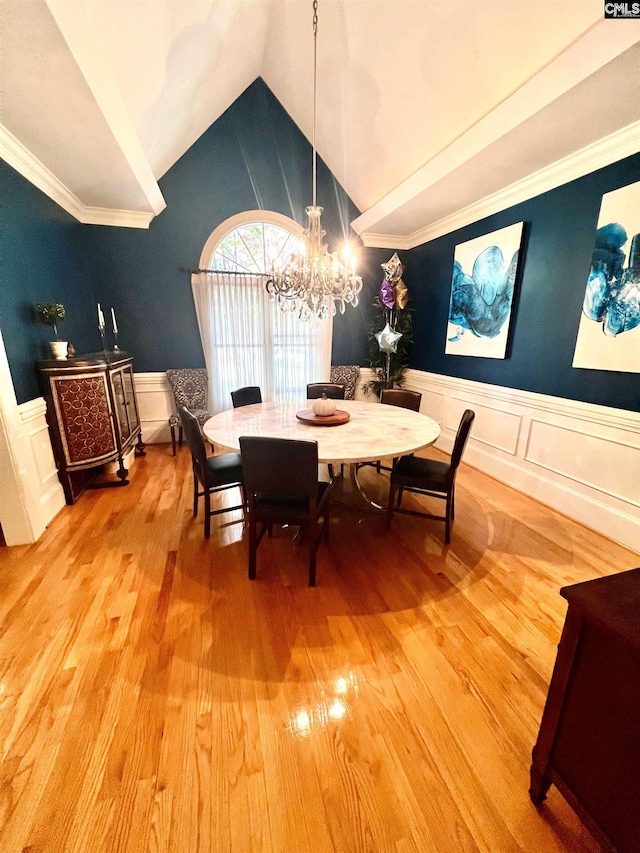 dining space with hardwood / wood-style flooring, a chandelier, ornamental molding, and vaulted ceiling