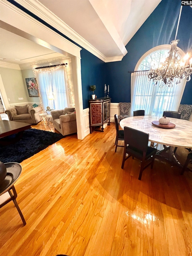 dining space featuring wood-type flooring, plenty of natural light, crown molding, and a notable chandelier