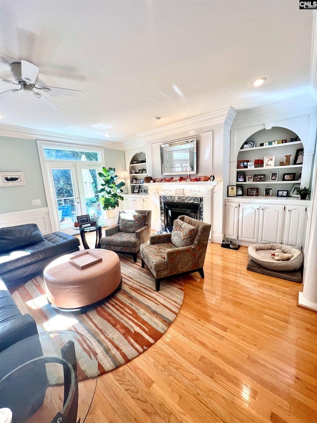 living room featuring crown molding, light hardwood / wood-style flooring, and built in features