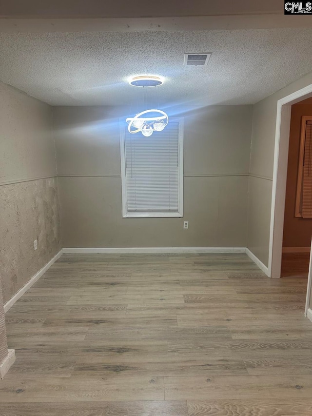 empty room with light hardwood / wood-style floors and a textured ceiling