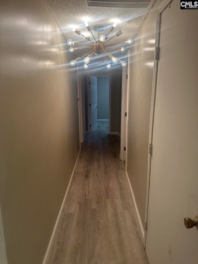 hallway with wood-type flooring and a textured ceiling