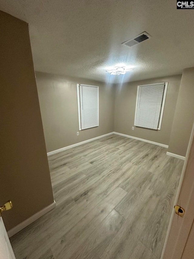 unfurnished room featuring light hardwood / wood-style flooring and a textured ceiling