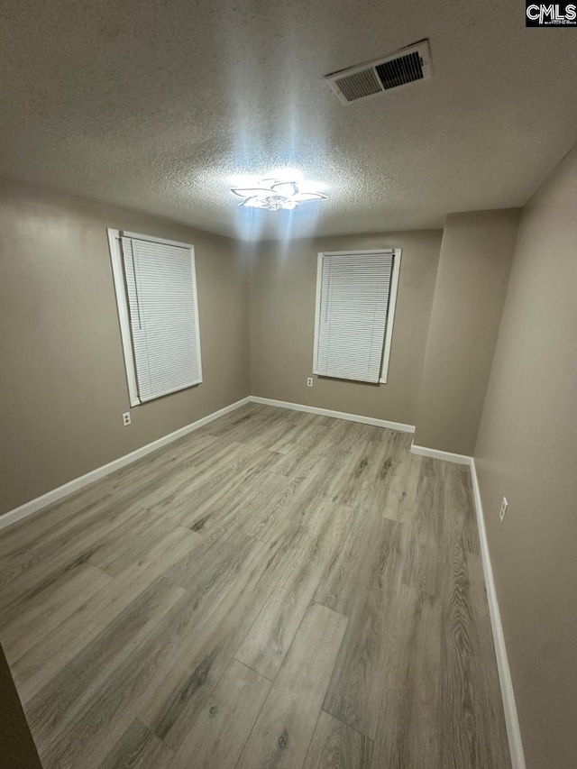 empty room featuring a textured ceiling and light hardwood / wood-style flooring