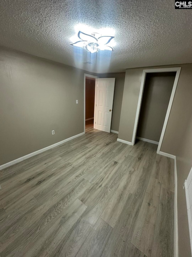 unfurnished bedroom with hardwood / wood-style floors, a textured ceiling, and a closet