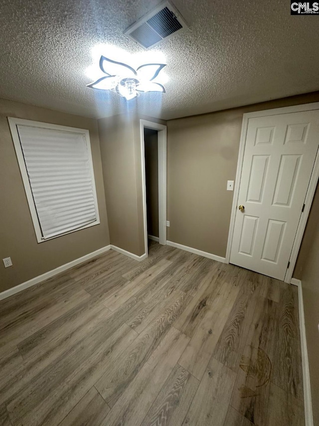 empty room featuring a textured ceiling and light wood-type flooring