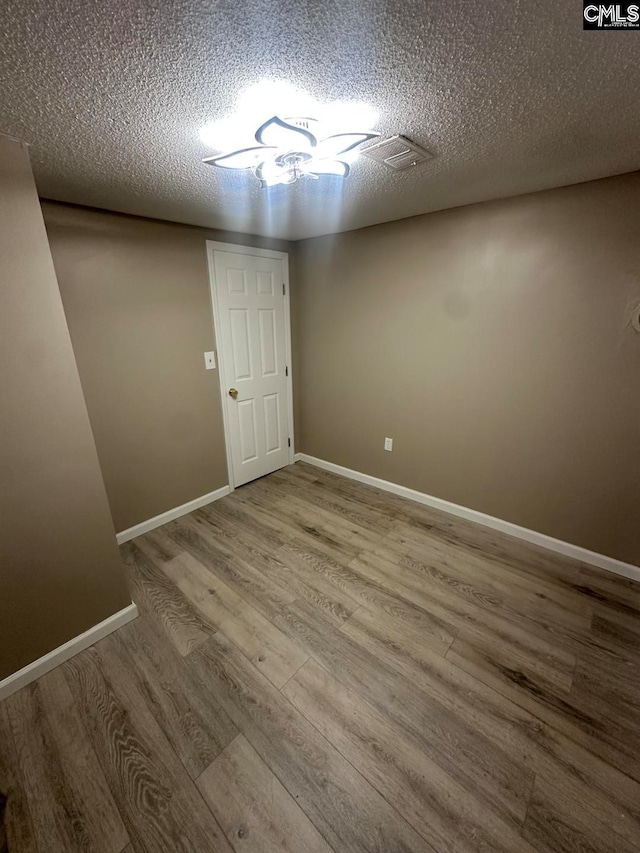 empty room featuring a textured ceiling and light hardwood / wood-style flooring