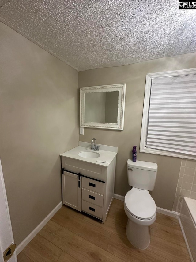 bathroom with hardwood / wood-style floors, vanity, a textured ceiling, and toilet