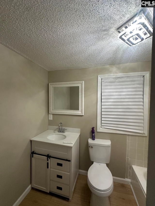 bathroom with hardwood / wood-style floors, vanity, toilet, and a tub