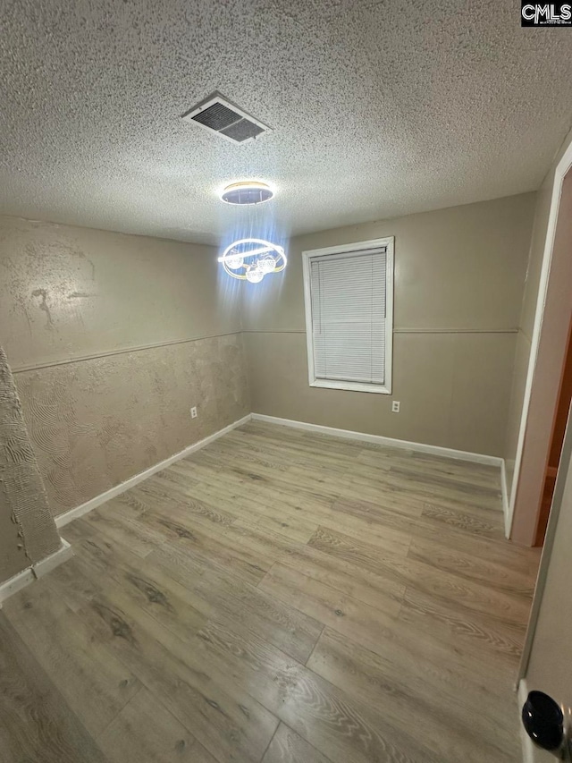 unfurnished dining area with wood-type flooring and a textured ceiling