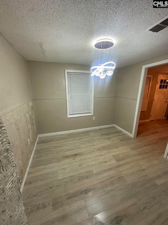 unfurnished dining area with a textured ceiling and hardwood / wood-style flooring