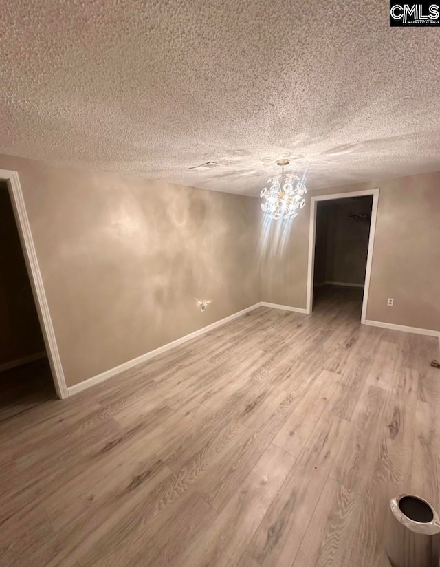 unfurnished room featuring hardwood / wood-style floors, a chandelier, and a textured ceiling