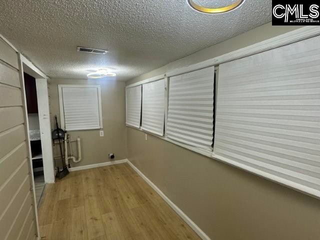 hallway with a textured ceiling and light hardwood / wood-style floors