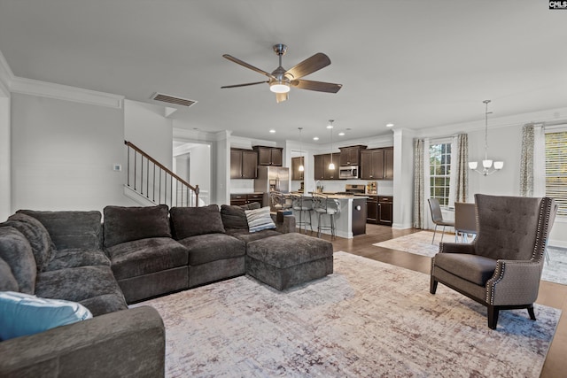 living room featuring crown molding, dark wood-type flooring, and ceiling fan with notable chandelier