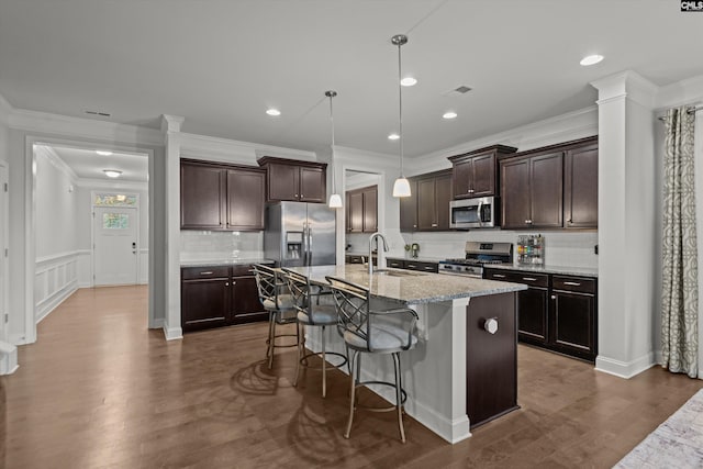 kitchen with a kitchen bar, a center island with sink, hanging light fixtures, dark hardwood / wood-style flooring, and stainless steel appliances