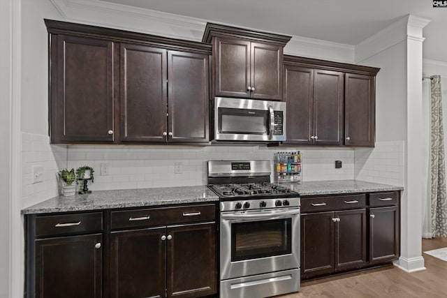 kitchen featuring decorative columns, crown molding, stainless steel appliances, and light hardwood / wood-style floors