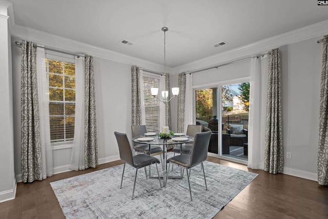 dining space featuring dark hardwood / wood-style flooring, crown molding, and a chandelier