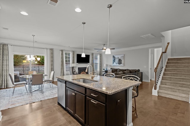 kitchen with a center island with sink, stainless steel dishwasher, a healthy amount of sunlight, and sink