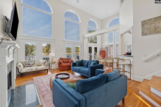 living room featuring a high ceiling, french doors, hardwood / wood-style floors, and a premium fireplace