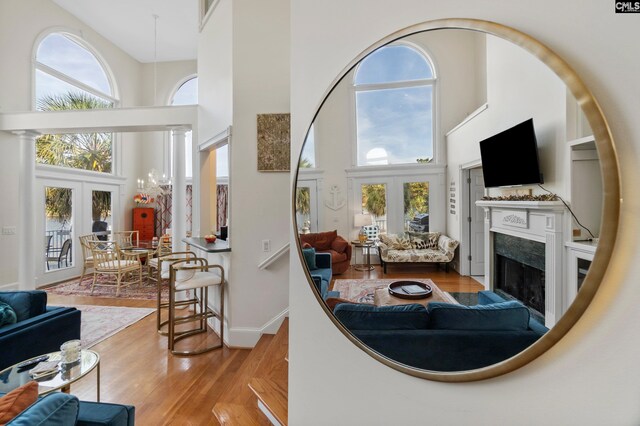 living room featuring light hardwood / wood-style flooring, a fireplace, a towering ceiling, and french doors