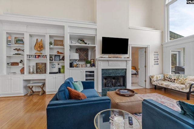 living room featuring a fireplace, a towering ceiling, and light hardwood / wood-style flooring