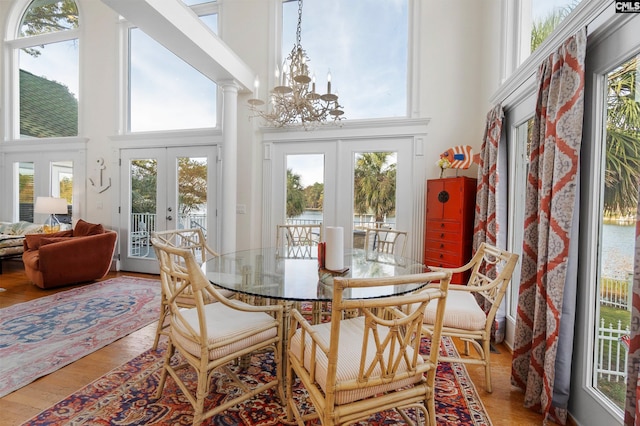 sunroom with french doors, a chandelier, and decorative columns